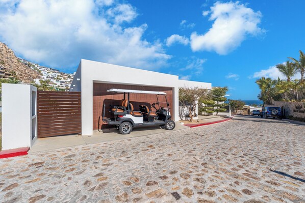 A modern building with a garage, a golf cart, and a cobblestone driveway.