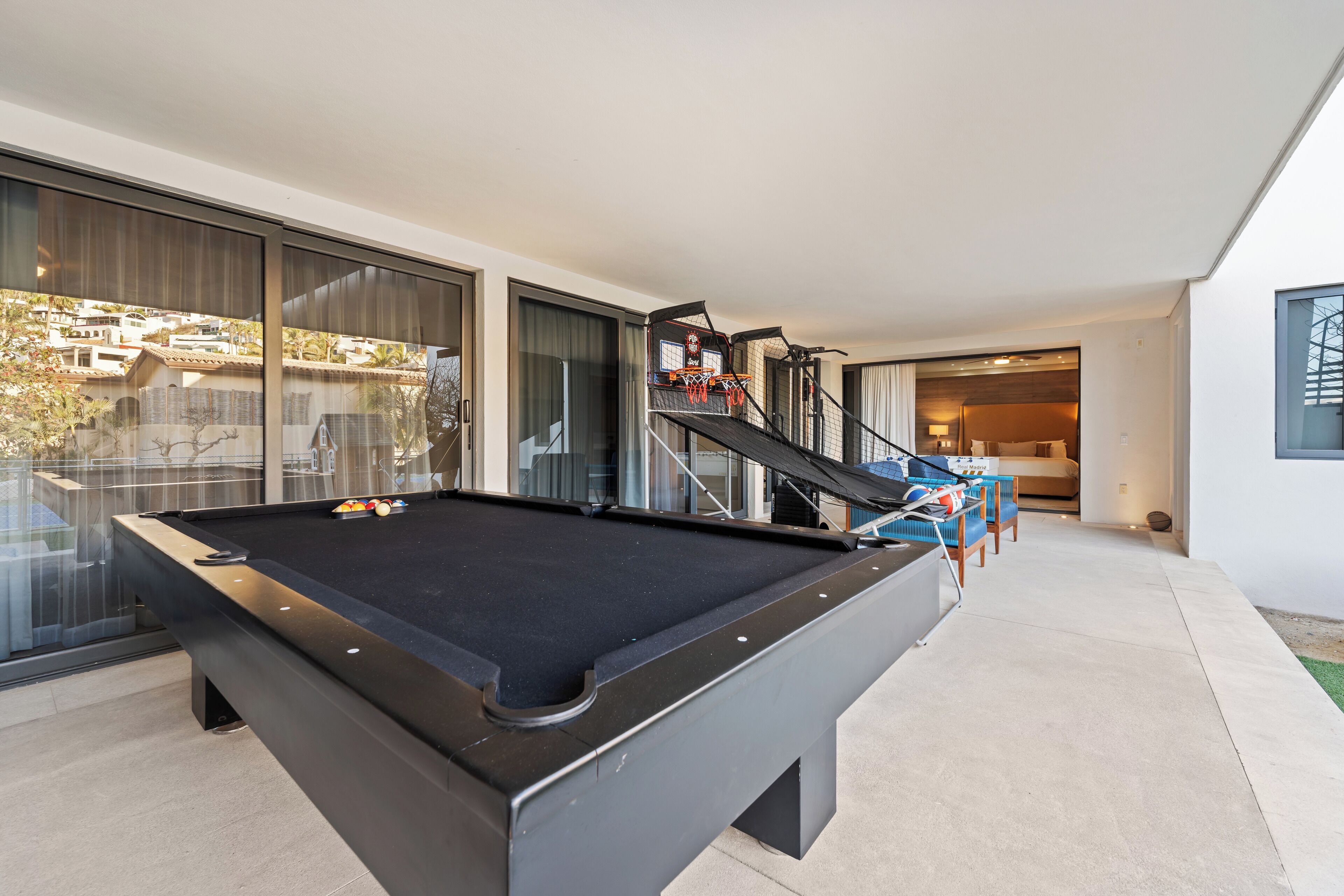 A pool table with a glass barrier and a staircase leading to a balcony.