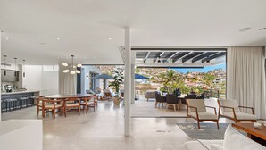 A spacious living area with a dining table, sofas, and a view of a hillside. - Villa Maravilla at Pedregal (Cabo San Lucas)