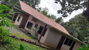 A single-story building with a red roof, surrounded by greenery and trees.