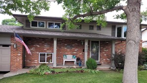 A two-story brick house with a front porch, an American flag, and a mailbox. - Exclusive 2 Bedroom Garden Level Apartment in Lovely Littleton Colorado! (Littleton)