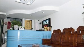 A reception area with a blue counter, wooden seating, and a television screen. - Longyao Hotel (Shanghai)