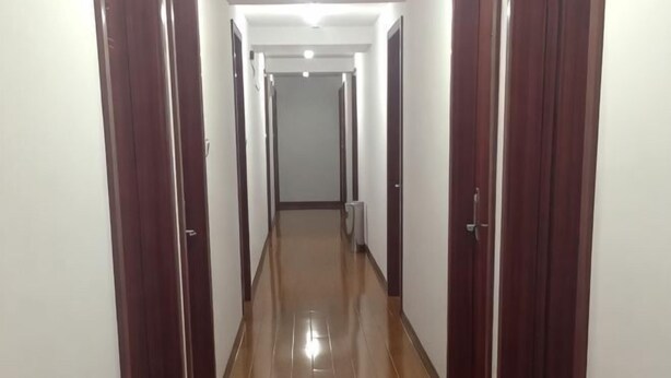 A long, narrow hallway with wooden doors on both sides and a shiny floor. - Longyao Hotel (Shanghai)