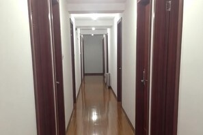 Un pasillo largo y estrecho con puertas de madera a ambos lados y un piso brillante.