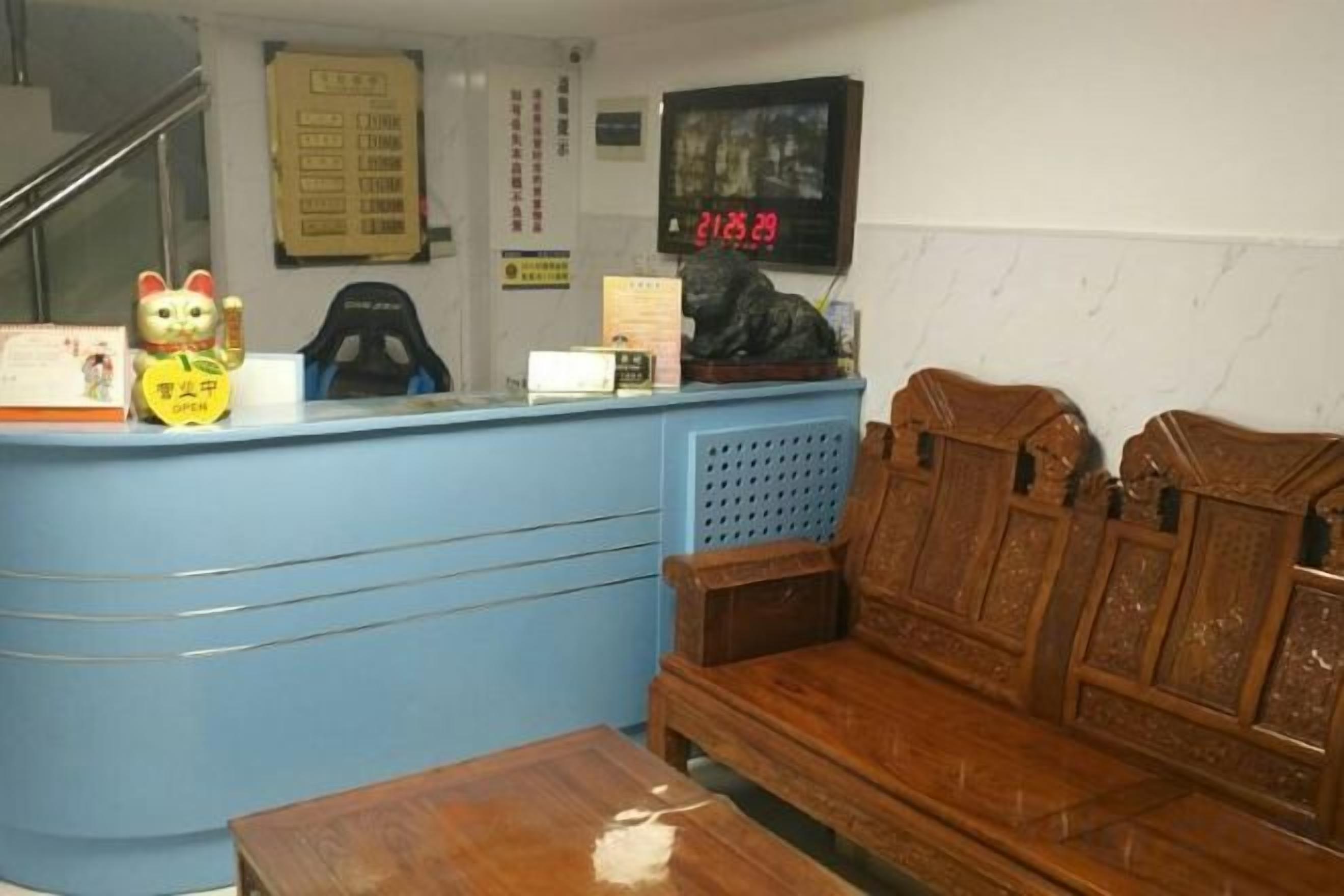 A reception area with a blue counter, wooden bench seating, a staircase, and a wall-mounted sign.