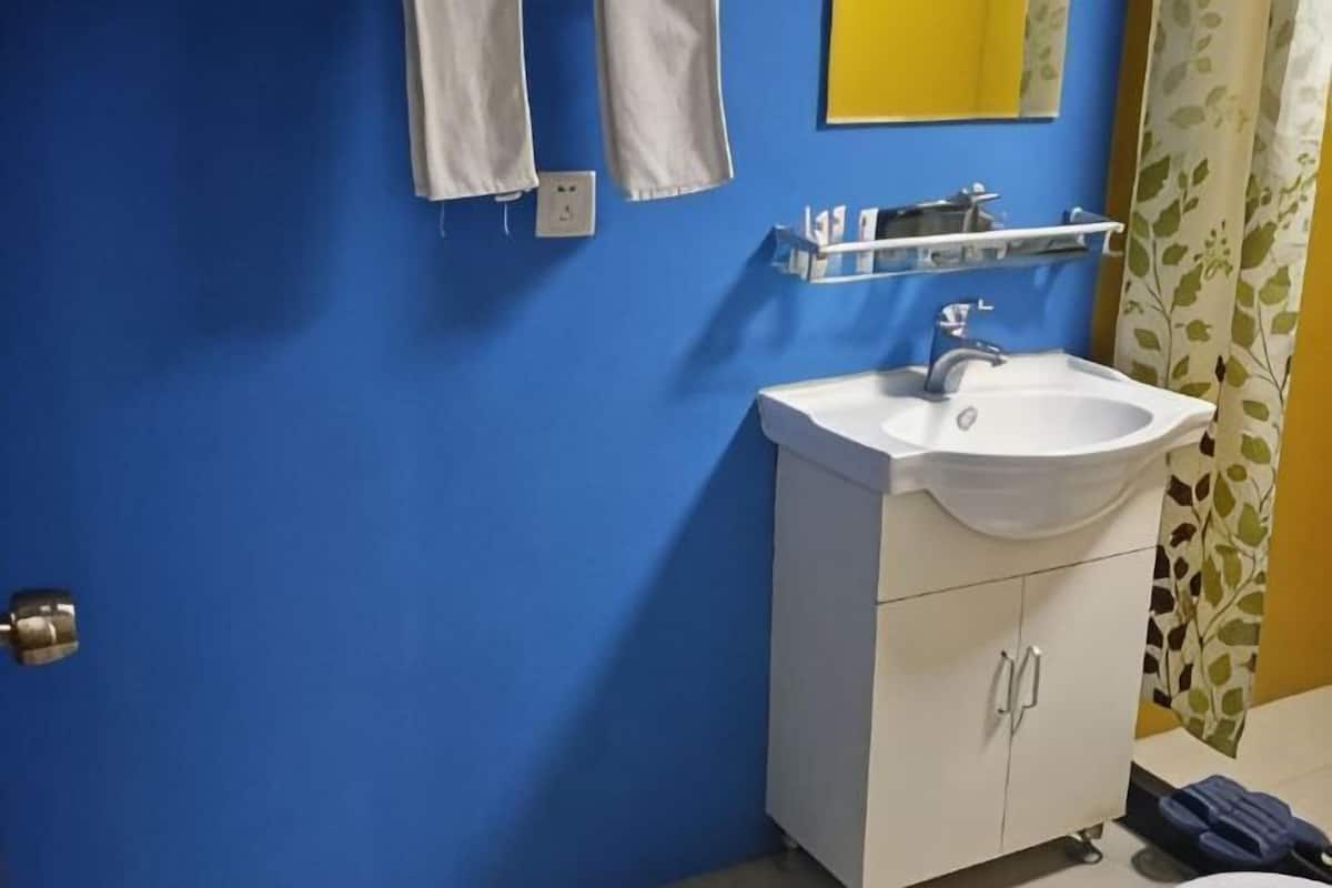 A bathroom with a white sink, blue walls, and a yellow mirror.