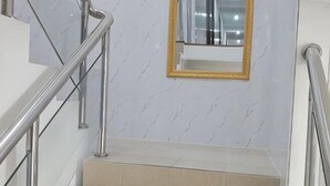 A staircase with metal railings, beige steps, and a marble wall with a gold-framed mirror. - Longyao Hotel (Shanghai)