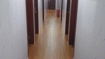 A narrow hallway with wooden flooring and white walls with a subtle pattern.
