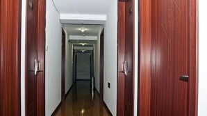 A hallway with wooden doors on both sides, leading to a room with a visible door at the end. - Longyao Hotel (Shanghai)