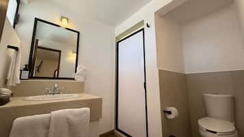 A bathroom with a sink, mirror, towel, toilet, and a door.
