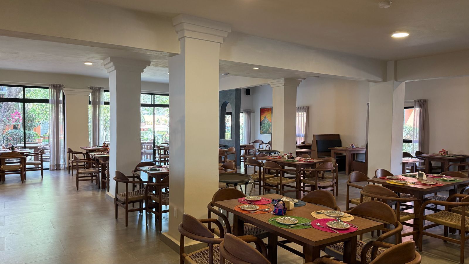Un vaste espace dédié à la salle à manger, avec de nombreuses tables et chaises, de grandes fenêtres et une vue sur l’extérieur.