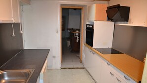 Een keuken met een spoelbak, fornuis en keukenkastjes.