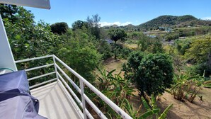A balcony with a view of a lush landscape, including trees and hills. - Beautiful home with 2 bedrooms 2 minutes from the beach. (Rincon)