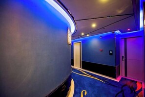 Een hotelgang met een gebogen plafond, blauwe wanden en een vloerkleed.