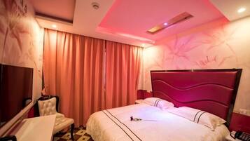 A hotel room with a bed, a desk, a chair, and a television.
