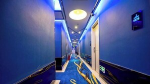 A hotel corridor with blue walls, a blue carpet with a logo, and a ceiling light. - Shanghai Innisfree Hotel (Huancheng East Road Subway Station Branch) (Shanghai)