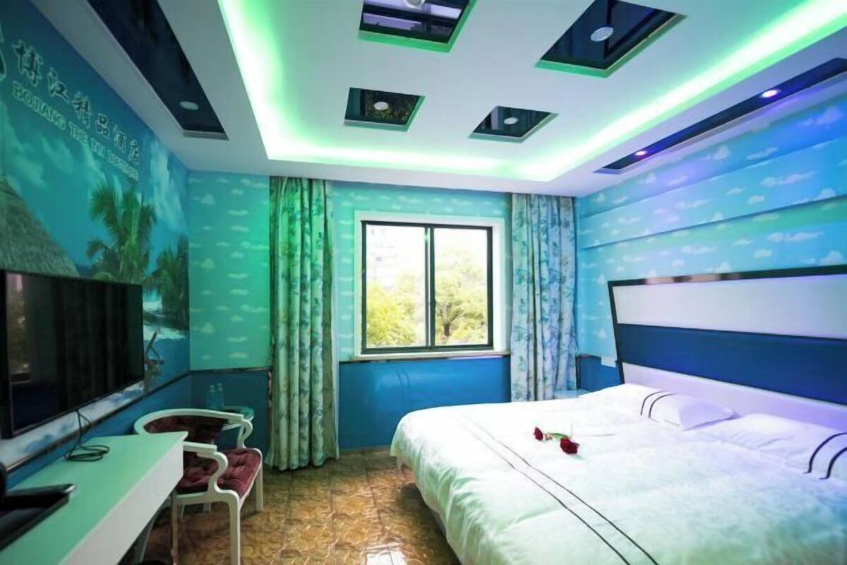 A hotel room with a bed, a TV, a desk, and a window.