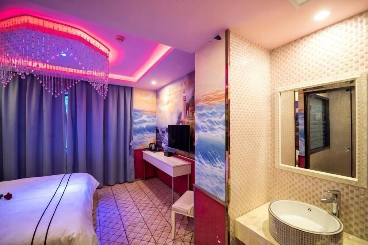 A hotel room with a bed, desk, TV, and bathroom.