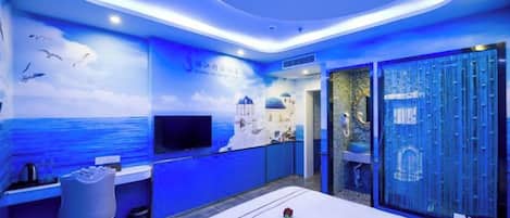 Una habitación de hotel con cama, escritorio, silla, televisor y vista al mar.