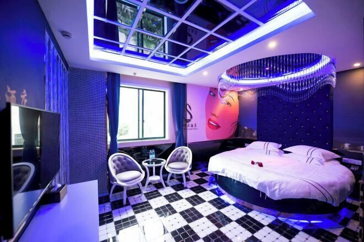 A modern bedroom with a checkered floor, a bed with white bedding, a chandelier, and a large window.