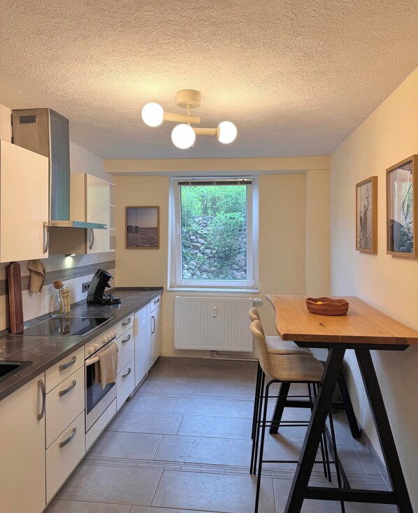 A compact kitchen with a window, a dining table, and a view of greenery outside.