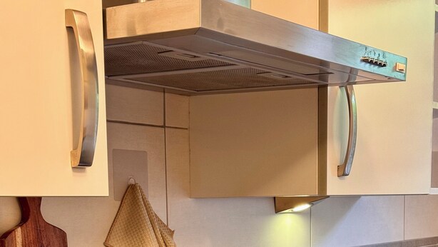 Una cocina moderna con tope de inducción negro, tabla de cortar de madera y dos saleros y pimenteros de madera.