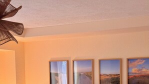 Una sala de estar moderna con un sofá modular, una mesa de centro redonda y tres cuadros con paisajes en la pared.