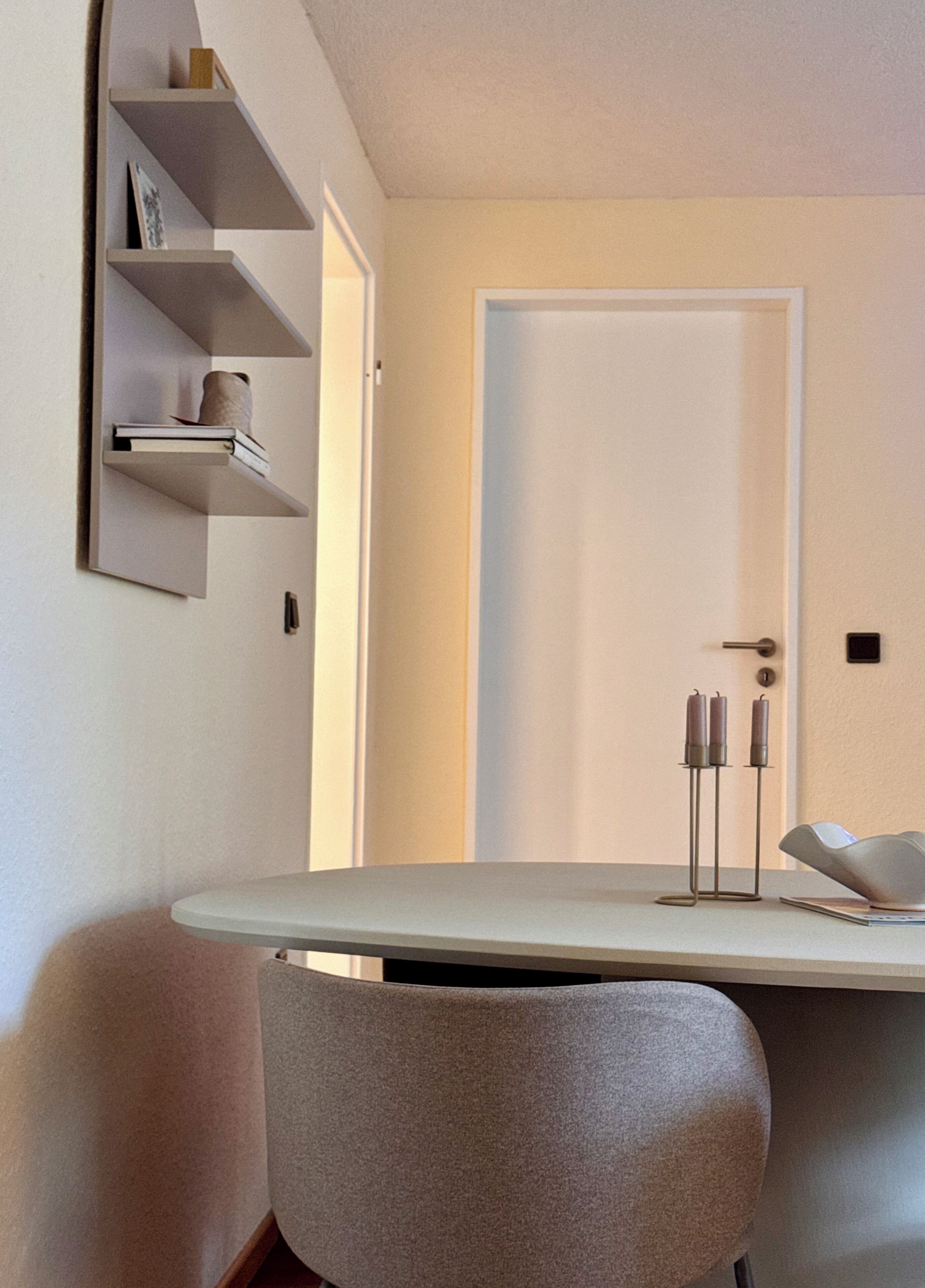 A modern room with a desk, a chair, a bookshelf, and a door.