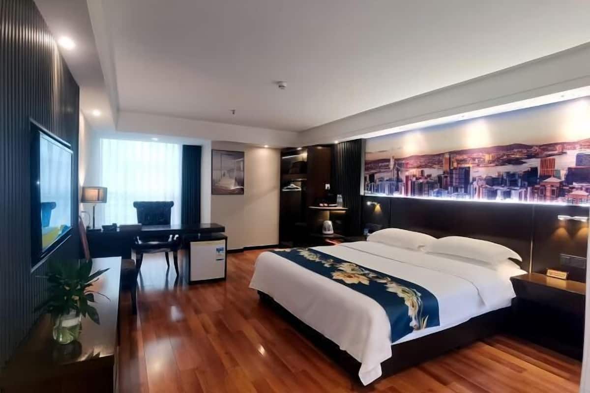 Une chambre d’hôtel moderne avec un grand lit, un bureau et une fresque représentant un paysage urbain sur le mur.