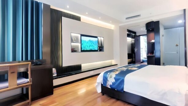 Una habitación de hotel moderna con una cama, un escritorio, un televisor montado en la pared y un armario.