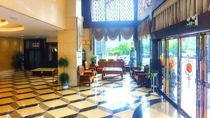 Un vestíbulo de hotel con piso a cuadros, zona de estar y ventanas amplias.