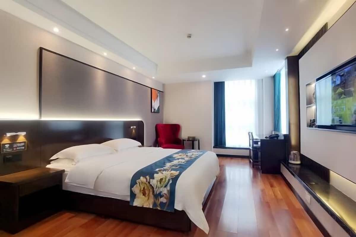 Une chambre d  ’hôtel moderne avec un grand lit, une télévision, un bureau et un fauteuil rouge.