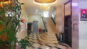 Un vestíbulo de hotel con suelo a cuadros, una escalera y un candelabro.