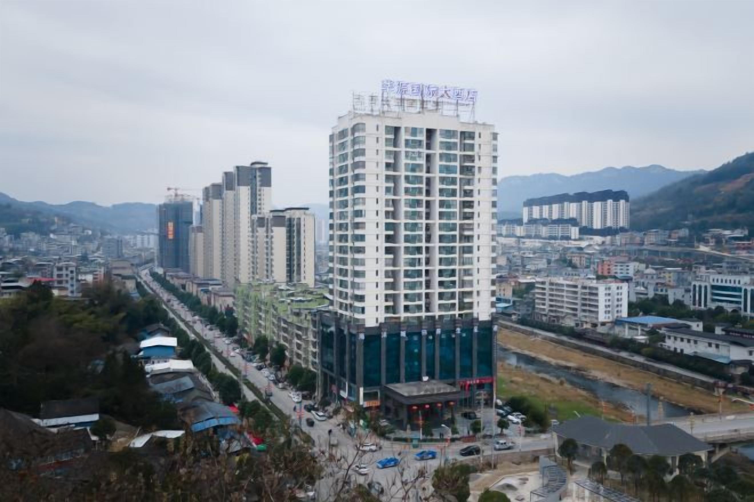 Un edificio alto con varios pisos, rodeado de otros edificios y un río.