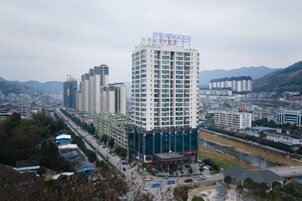 Un edificio alto con varios pisos, rodeado de otros edificios y un río.