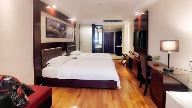 Habitación de hotel con una cama grande, un escritorio con silla, un televisor y un cuadro en la pared.
