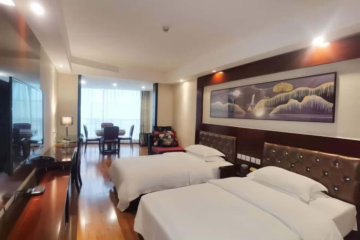 Une chambre d’hôtel avec deux lits, un coin repas et un grand tableau au mur.