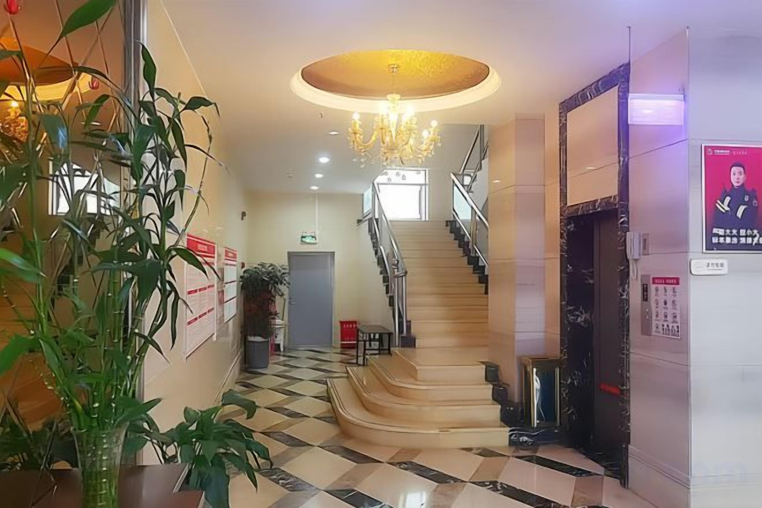 Un'hall di un hotel con una scala, un lampadario e una pianta.