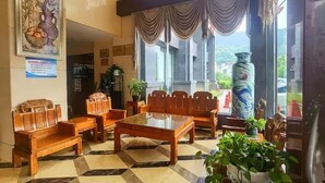 Un vestíbulo con muebles de madera, suelo a cuadros, un jarrón grande y un cuadro en la pared.