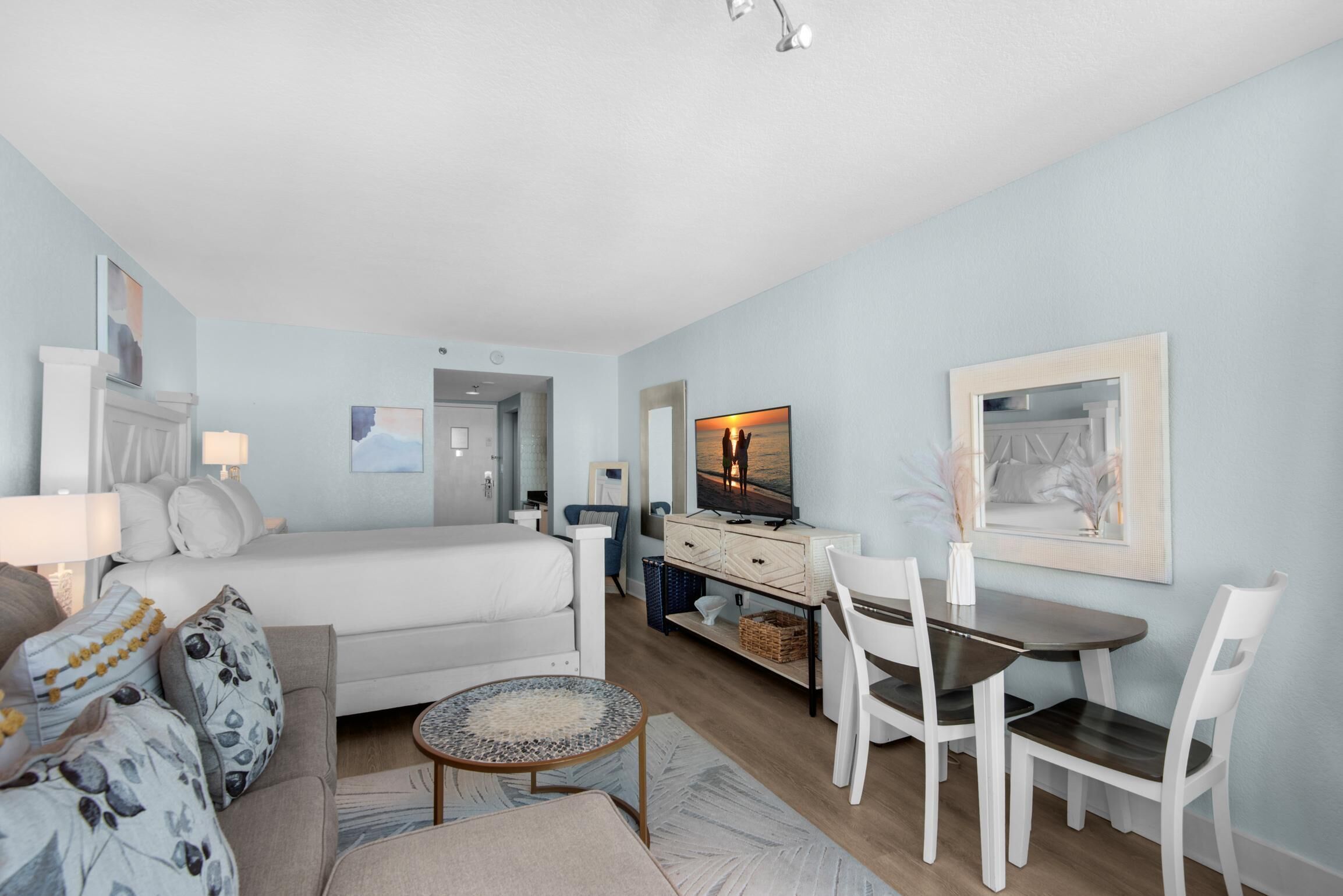 A modern bedroom with a bed, bedside tables, a dresser, and a TV.
