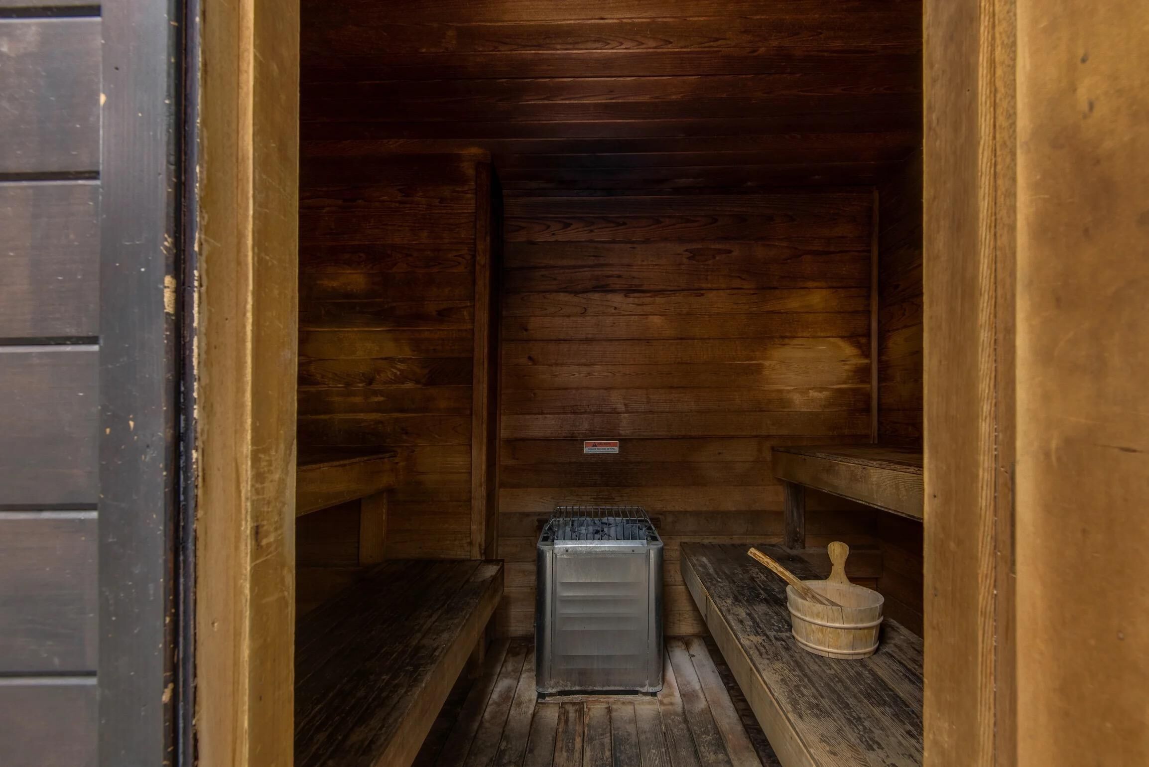 A wooden cabin interior with benches and a metal container.