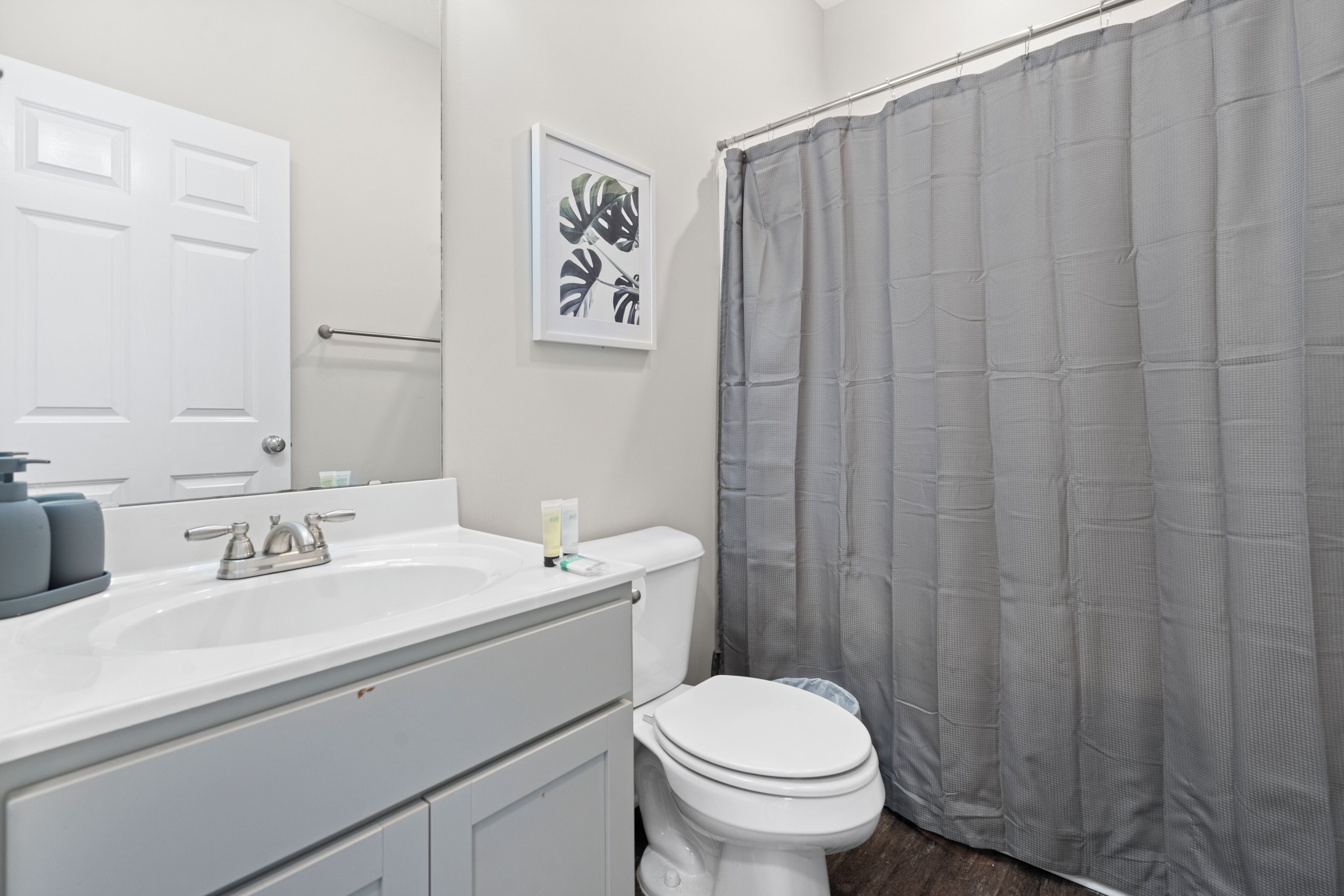 A bathroom with a white sink, a toilet, and a shower curtain.