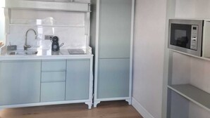 Eine Küche mit weißer Arbeitsplatte, Spüle, Kaffeemaschine und Mikrowelle.