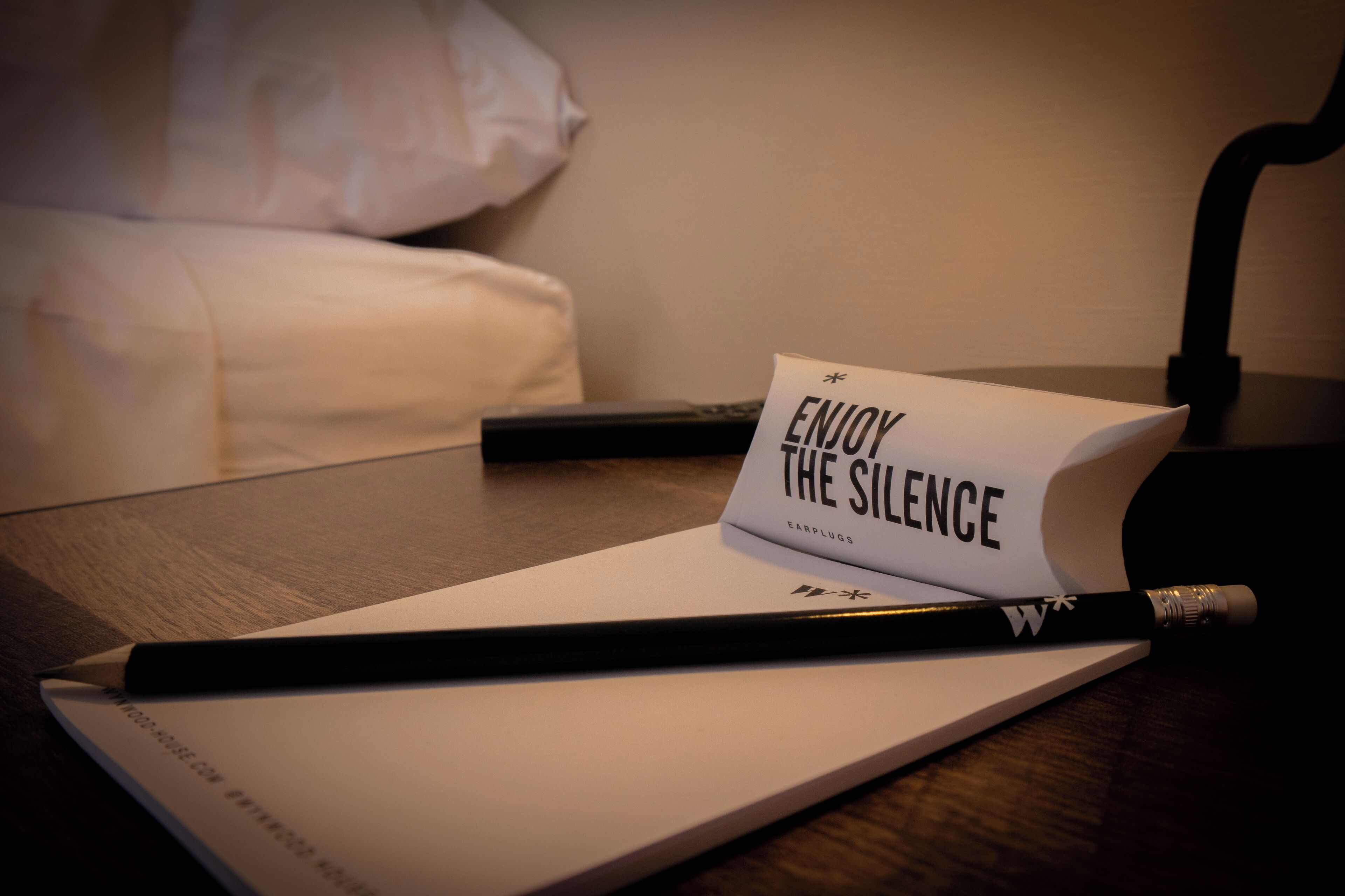 A notebook with a pencil and a card that reads "ENJOY THE SILENCE" on a wooden table.