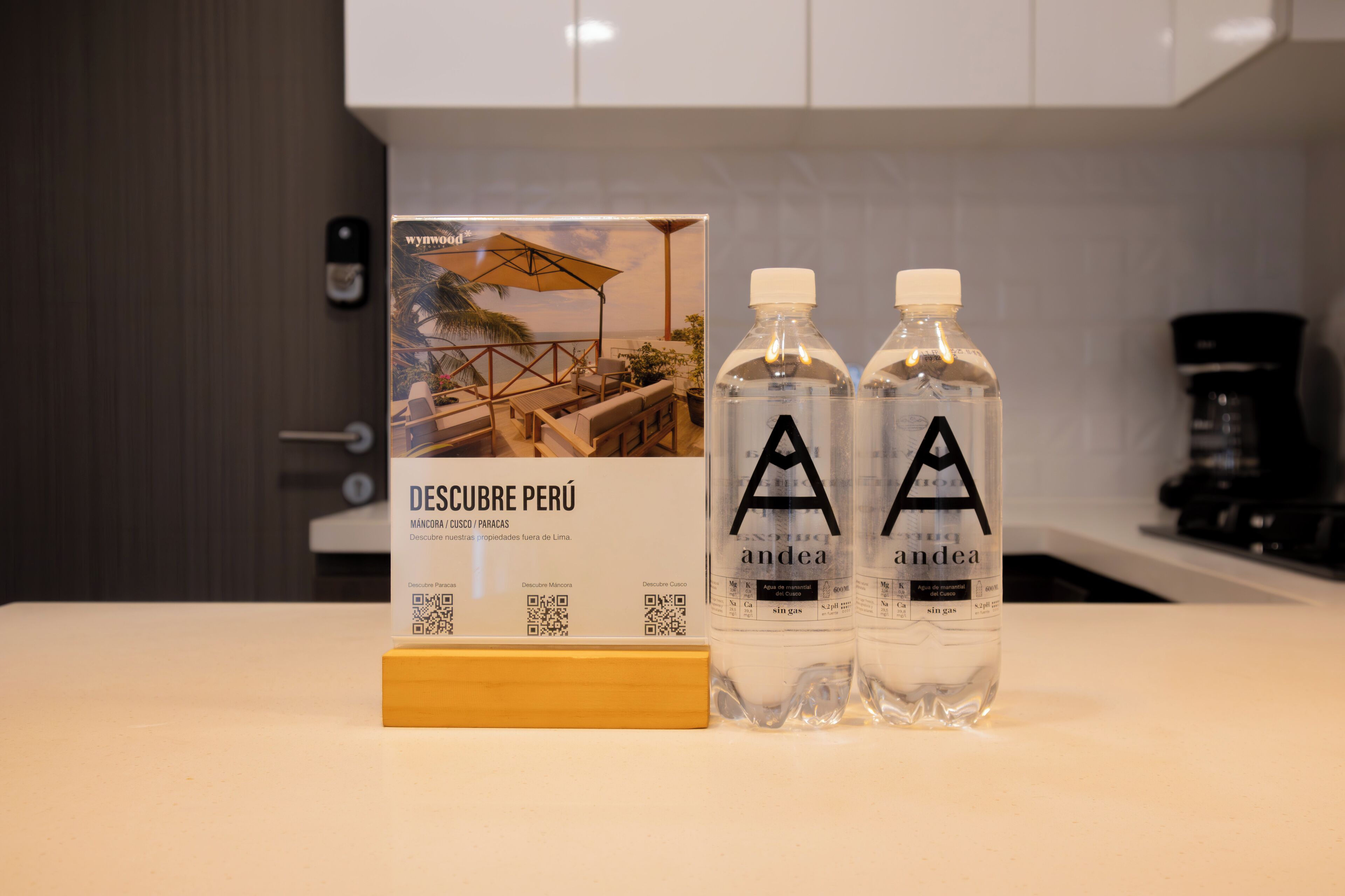A hotel sign with a beach view and two bottles of 'andea' water on a counter.
