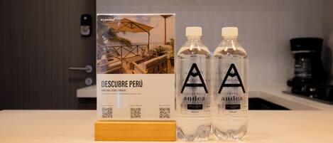 A hotel sign with a beach view and two bottles of 'andea' water on a counter.