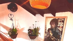 A room with a hanging light fixture, two potted plants, and a framed photograph on a draped white cloth. - Boutique Stay Near Pereira (Dosquebradas)
