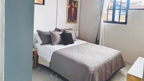 A bedroom with a bed, a nightstand, a window with curtains, a framed picture on the wall, and a wooden ceiling. - Boutique Stay Near Pereira (Dosquebradas)