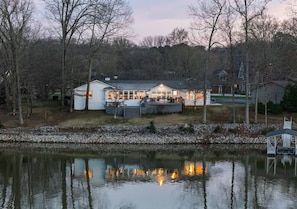 Une propriété au bord du lac, comprenant une grande maison, un quai et un petit bateau.