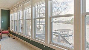 Una habitación con ventanas amplias, vistas a un muelle y una silla.